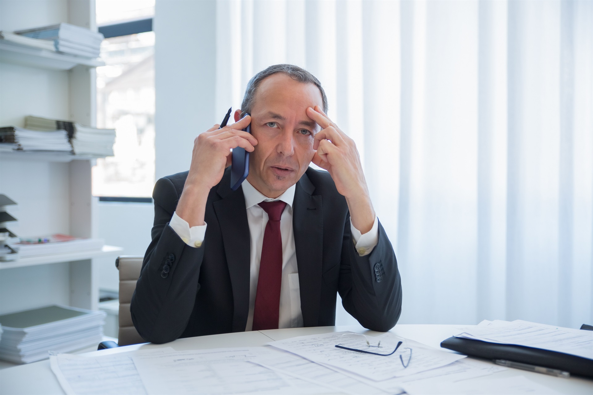 Advogado ao telefone em meio a processos, atendendo mais uma cobrança de status